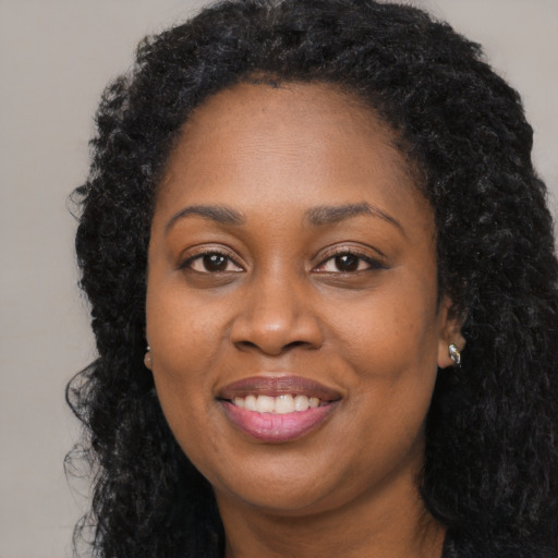 Joyful black young-adult female with long  black hair and brown eyes