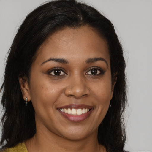 Joyful black young-adult female with long  brown hair and brown eyes