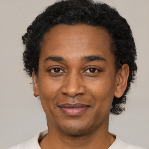 Joyful black adult male with short  black hair and brown eyes
