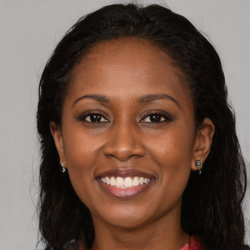 Joyful black young-adult female with long  brown hair and brown eyes