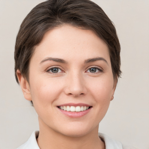 Joyful white young-adult female with short  brown hair and grey eyes