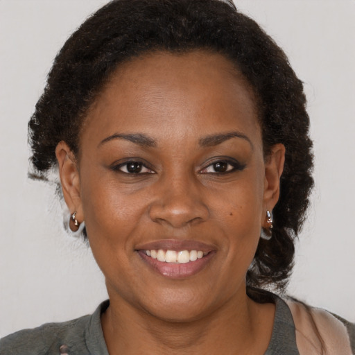 Joyful black adult female with medium  brown hair and brown eyes