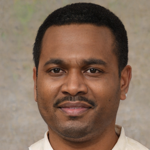 Joyful black young-adult male with short  black hair and brown eyes
