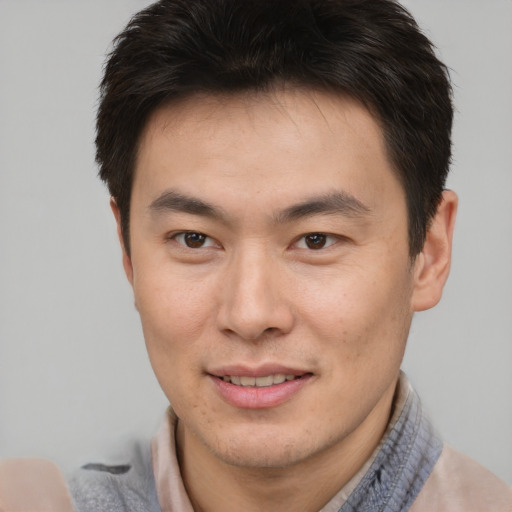 Joyful asian young-adult male with short  brown hair and brown eyes