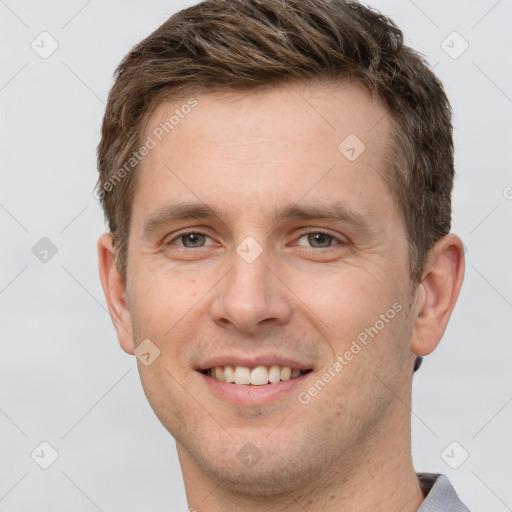 Joyful white young-adult male with short  brown hair and grey eyes