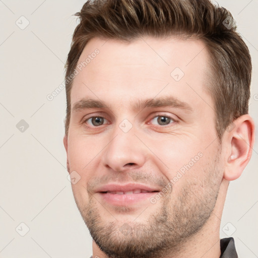 Joyful white young-adult male with short  brown hair and grey eyes