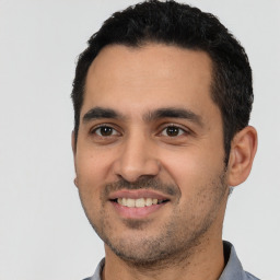 Joyful latino young-adult male with short  black hair and brown eyes