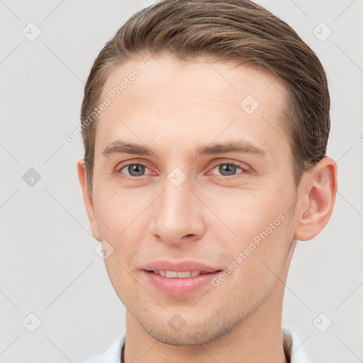 Joyful white young-adult male with short  brown hair and grey eyes