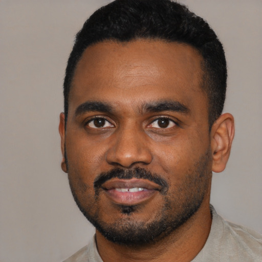 Joyful black young-adult male with short  black hair and brown eyes