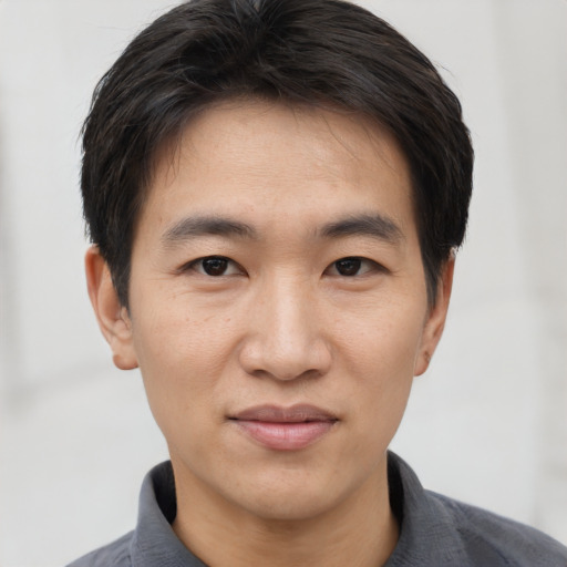 Joyful asian young-adult male with short  black hair and brown eyes