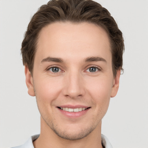 Joyful white young-adult male with short  brown hair and grey eyes