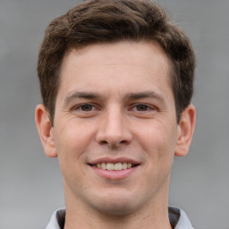 Joyful white young-adult male with short  brown hair and grey eyes