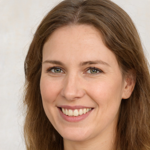 Joyful white young-adult female with long  brown hair and green eyes