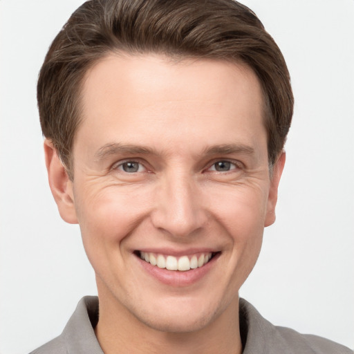 Joyful white young-adult male with short  brown hair and grey eyes