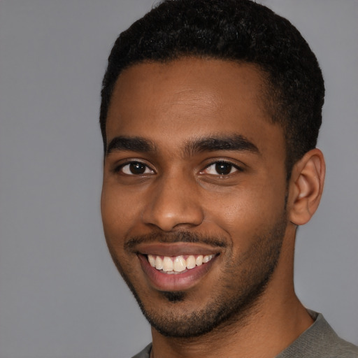 Joyful black young-adult male with short  black hair and brown eyes