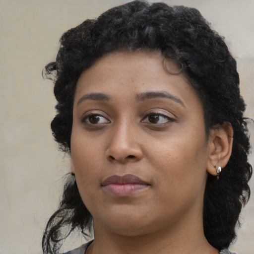 Joyful black young-adult female with long  black hair and brown eyes