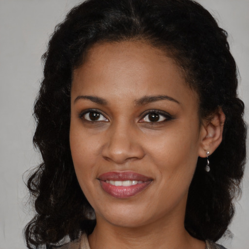 Joyful black young-adult female with long  brown hair and brown eyes