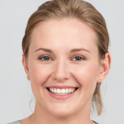 Joyful white young-adult female with medium  brown hair and grey eyes