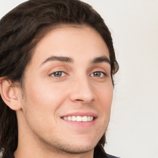 Joyful white young-adult male with long  brown hair and brown eyes