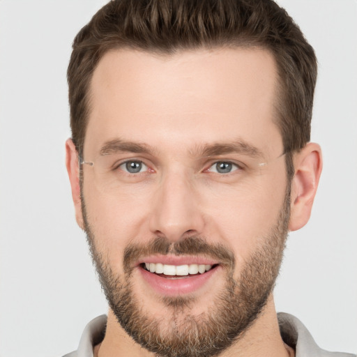 Joyful white young-adult male with short  brown hair and grey eyes