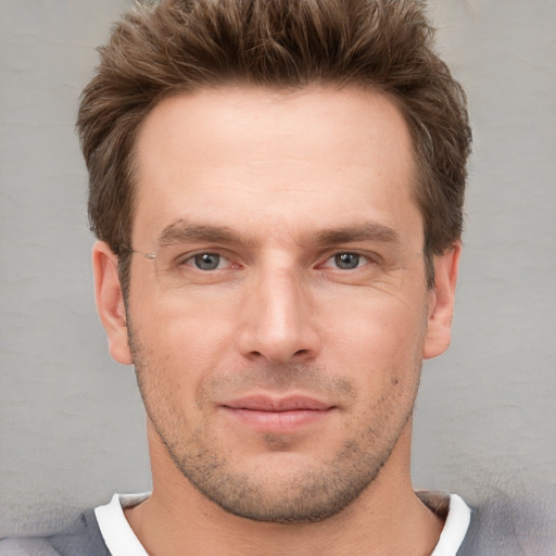 Joyful white young-adult male with short  brown hair and grey eyes