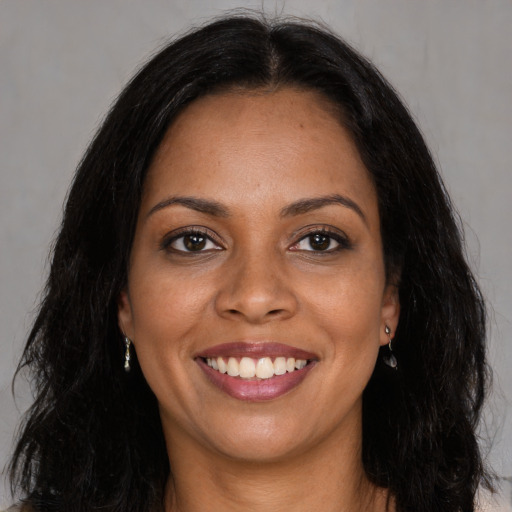 Joyful black young-adult female with long  brown hair and brown eyes