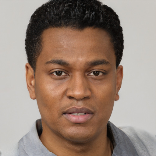 Joyful black young-adult male with short  black hair and brown eyes