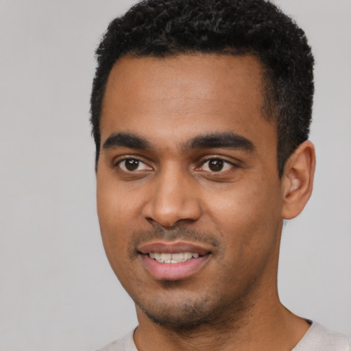 Joyful black young-adult male with short  black hair and brown eyes