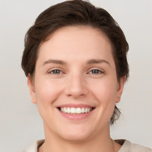 Joyful white young-adult female with short  brown hair and grey eyes