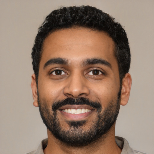 Joyful black young-adult male with short  black hair and brown eyes
