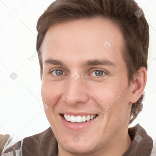 Joyful white young-adult male with short  brown hair and grey eyes