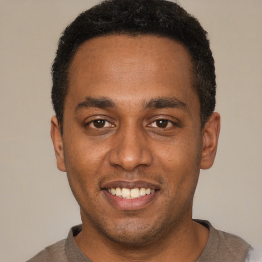 Joyful black young-adult male with short  black hair and brown eyes