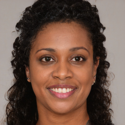 Joyful black young-adult female with long  brown hair and brown eyes