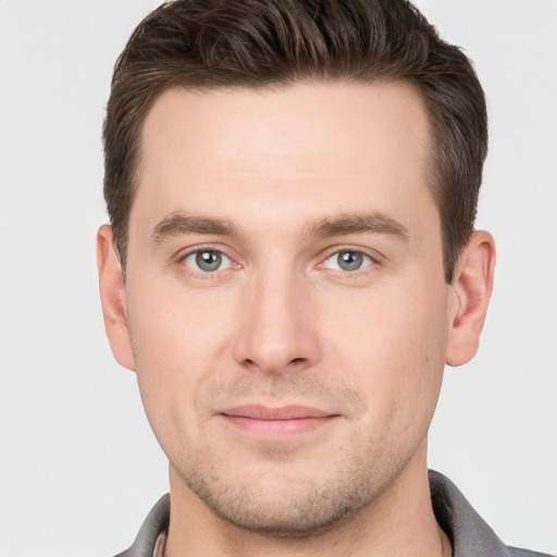 Joyful white young-adult male with short  brown hair and grey eyes