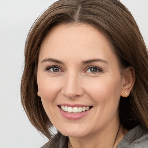 Joyful white young-adult female with medium  brown hair and grey eyes