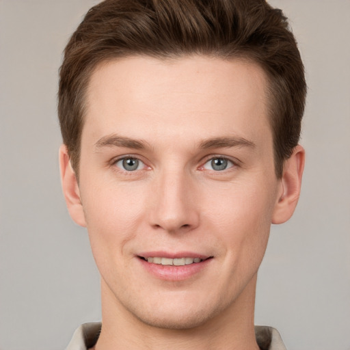 Joyful white young-adult male with short  brown hair and grey eyes