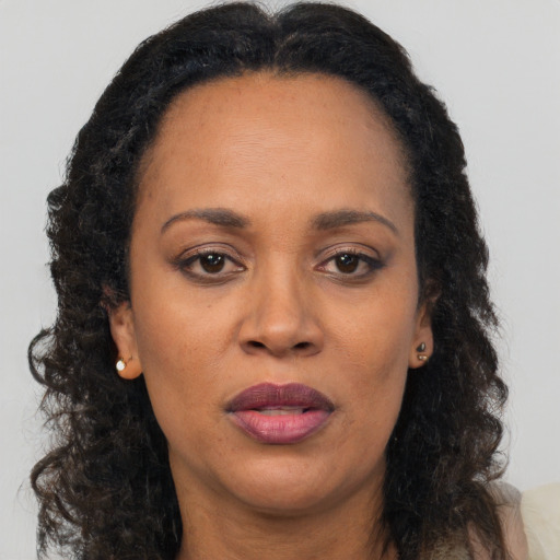Joyful black adult female with long  brown hair and brown eyes