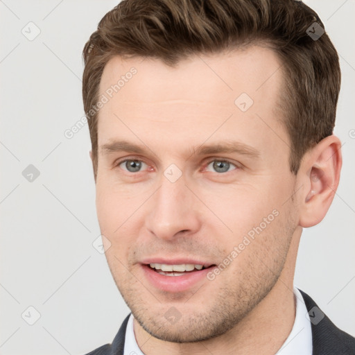 Joyful white young-adult male with short  brown hair and grey eyes