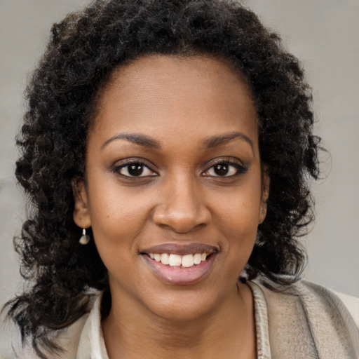 Joyful black young-adult female with long  brown hair and brown eyes