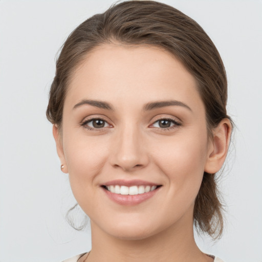 Joyful white young-adult female with medium  brown hair and grey eyes