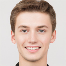 Joyful white young-adult male with short  brown hair and grey eyes