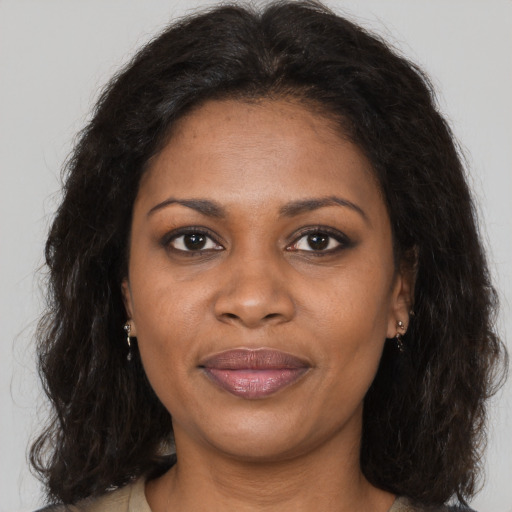 Joyful black young-adult female with long  brown hair and brown eyes