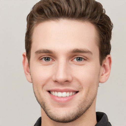 Joyful white young-adult male with short  brown hair and grey eyes