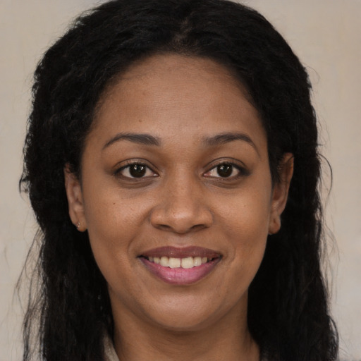 Joyful black adult female with long  brown hair and brown eyes