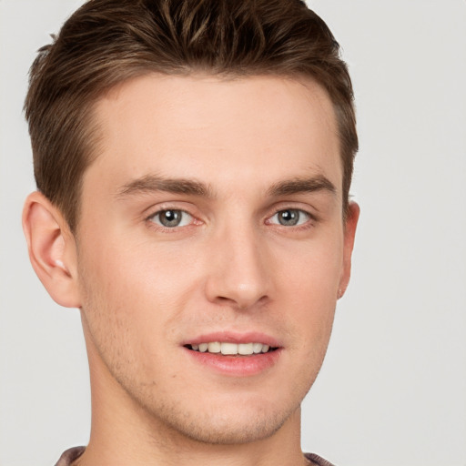 Joyful white young-adult male with short  brown hair and grey eyes