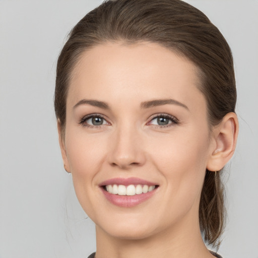 Joyful white young-adult female with medium  brown hair and grey eyes