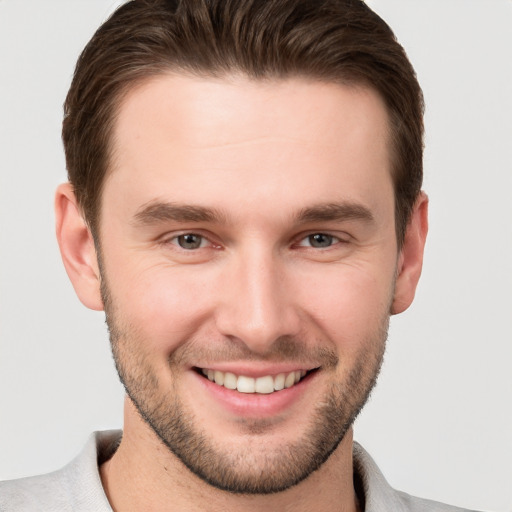 Joyful white young-adult male with short  brown hair and grey eyes