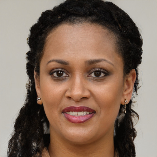 Joyful black young-adult female with long  brown hair and brown eyes