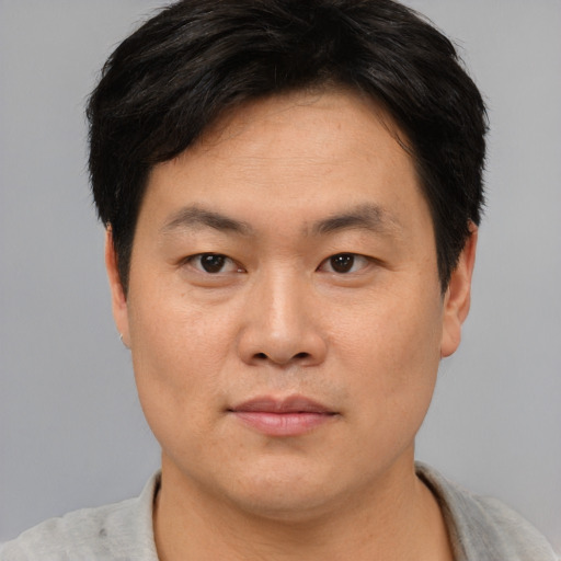 Joyful asian adult male with short  brown hair and brown eyes