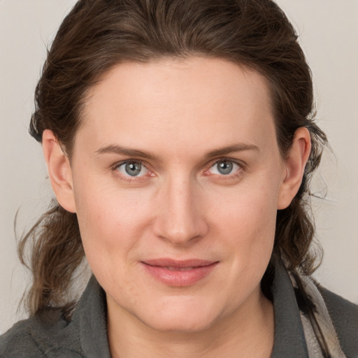 Joyful white young-adult female with medium  brown hair and grey eyes